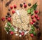Cereal oat flakes pile with spoon and fresh delicious berries on wooden background