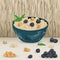 Cereal porridge in bowl with blueberry, hazelnut and mint leaves on wooden background