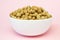 Cereal rye and oats breakfast balls in white ceramic bowl on pink background, side view