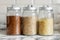 Cereals in the kitchen. Glass jars with buckwheat, rice and barley on a marble countertop