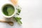 Ceremony green matcha tea and bamboo whisk on white concrete table. Top view