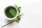 Ceremony green matcha tea and bamboo whisk on white concrete table. Top view