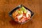 Ceviche in a black bowl with a generous serving of prawns, tomato, avocado, parsley