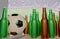 CGI 3D still life design of group of beer bottles , football and TV remote on table in front of big television LCD screen in