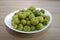 Chaenomeles japonica fruits on the white plate. Wooden background.