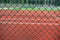 Through the chain-link fence, a blurred tennis court beckons, enticing players to the game and sporting competition.