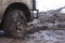 Chained up tire on a very muddy road.