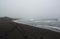 The chains of footprints on a black volcanic sand. A gloomy landscape - Khalaktyrsky beach in stormy weather in august