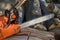 Chainsaw that stands on a heap of firewood in the yard on a background of firewood and trees cut by a chainsaw