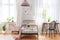 Chair at desk next to bed in pink and white girl`s room interior with plants and windows