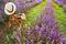 A chair with a hanged over hat, an open book, a retro camera and a bunch of lavender flowers between the blooming lavender rows un