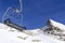 Chair lift in the foreground against the background of snow-capped mountains and blue sky.Austrian Alps in winter