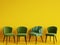 A chair with pattern colorful stripes among simple green chairs on yellow backgrond with copy space