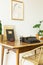 Chair at wooden desk with typewriter in classic workspace interior with poster on white wall. Real photo