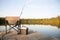 A Chair on a Wooden Dock Looking Out on a Lake in Summer with Fishing Equipment