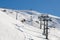 Chairlift lifts skiers and snowboarders to the top of the mountain in a winter sunny day
