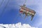 Chairlifts with skiers from below on blue sky and peak mountain snowy