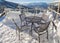 Chairs on a snow covered deck with a chairlift tower in the background.