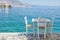 Chairs with tables in typical Greek tavern near the sea in Symi town