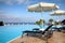Chaise longues and beach parasols near infinity pool at resort
