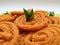 Chakli in a Green Plate  on White Background. Indian Snack Chakli or chakali made from deep frying portions of a lentil