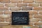 Chalk board with the word EXPLORE drown by hand and chalks on wooden table on brick wall background