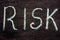 Chalk inscription `risk` on a black board.