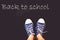 chalk and kid& x27;s feet on black background wearing sneakers - back to school concept