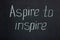 Chalk lettering on dark board Aspire to inspire