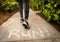 Chalk letters on sidewalk stating RUN with legs and shoes of woman in yoga pants blurred while running away