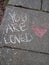 Chalk Writing on Sidewalk You Are Loved with Pink Heart