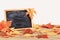 Chalkboard and autumnal leaves on wooden table