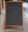 Chalkboard blank with wooden frame outdoors on a sidewalk