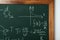 Chalkboard with many different math formulas on white wall, closeup