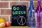 Chalkboard notice, Go Green, No straws today with no straws symbol, on table with water bottles and fruit