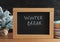 Chalkboard with phrase Winter Break, small Christmas tree and books on wooden table. Holidays concept