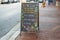 A chalkboard sandwich board that lists health measures for customers dining in