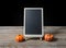 The chalkboard on the stand with Halloween Pumpkins on wooden fl