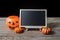 The chalkboard on the stand with Halloween Pumpkins on wooden fl