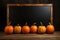 Chalkboard stand, pumpkins on wooden floor, set against intense black backdrop