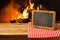 Chalkboard on wooden table over fireplace background. Winter and Christmas holiday