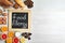 Chalkboard with words FOOD ALLERGY and different products on white table. Space for text