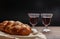 Challah bread with two glasses of red wine on wooden table