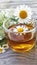 Chamomile aromatic tea in a glass cup on a wooden background. Summer still life with a bouquet of wildflowers and a medicinal