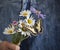 Chamomile and butterfly in woman hands on summer jeans overalls background