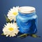 Chamomile cream. Face and body care. Cosmetics in small jar near chamomile flowers on blue background copy space