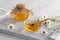 Chamomile syrup in a small bowl and in a jar on a white wooden table