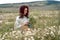 Chamomile woman. Happy curly woman in a chamomile field, dressed in a white dress.