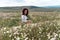 Chamomile woman. Happy curly woman in a chamomile field, dressed in a white dress.