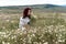 Chamomile woman. Happy curly woman in a chamomile field, dressed in a white dress.